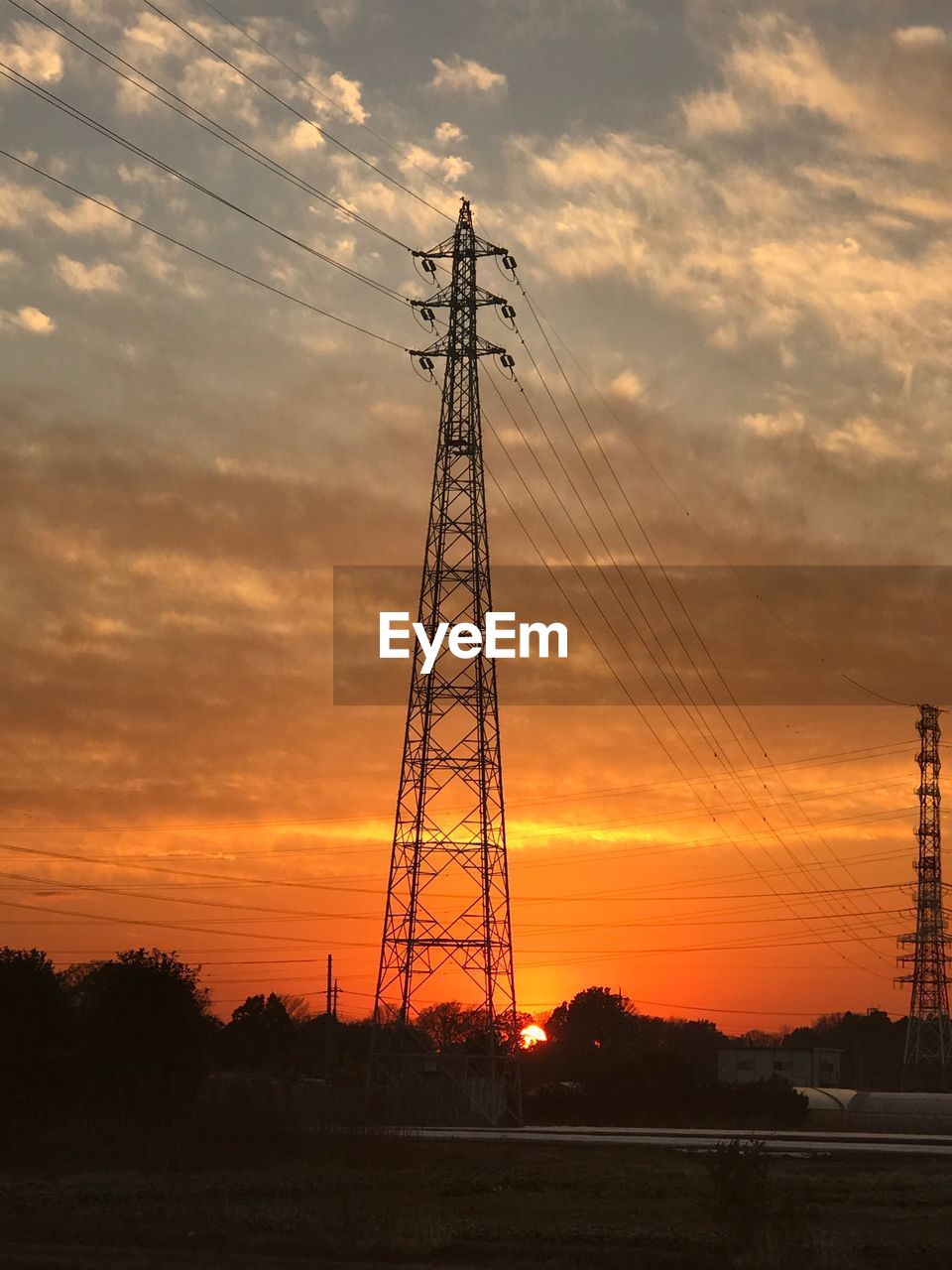 LOW ANGLE VIEW OF ELECTRICITY PYLON AGAINST ORANGE SKY