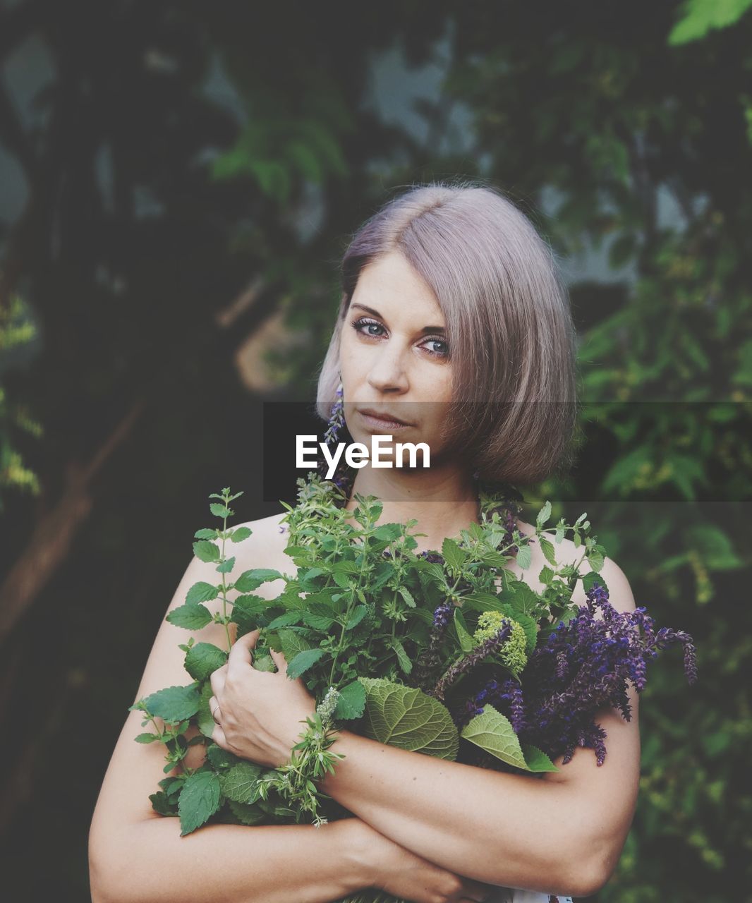 PORTRAIT OF YOUNG WOMAN WITH PLANTS IN HAIR