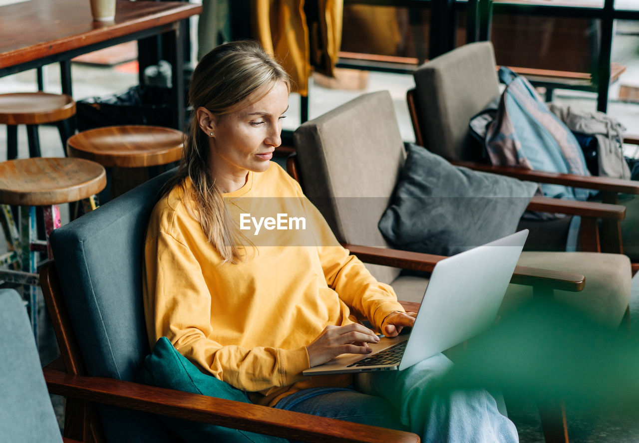 A woman sitting in a coworking space works on a laptop.