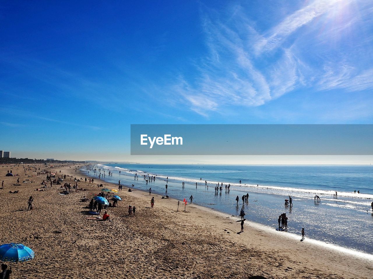 People on beach against blue sky