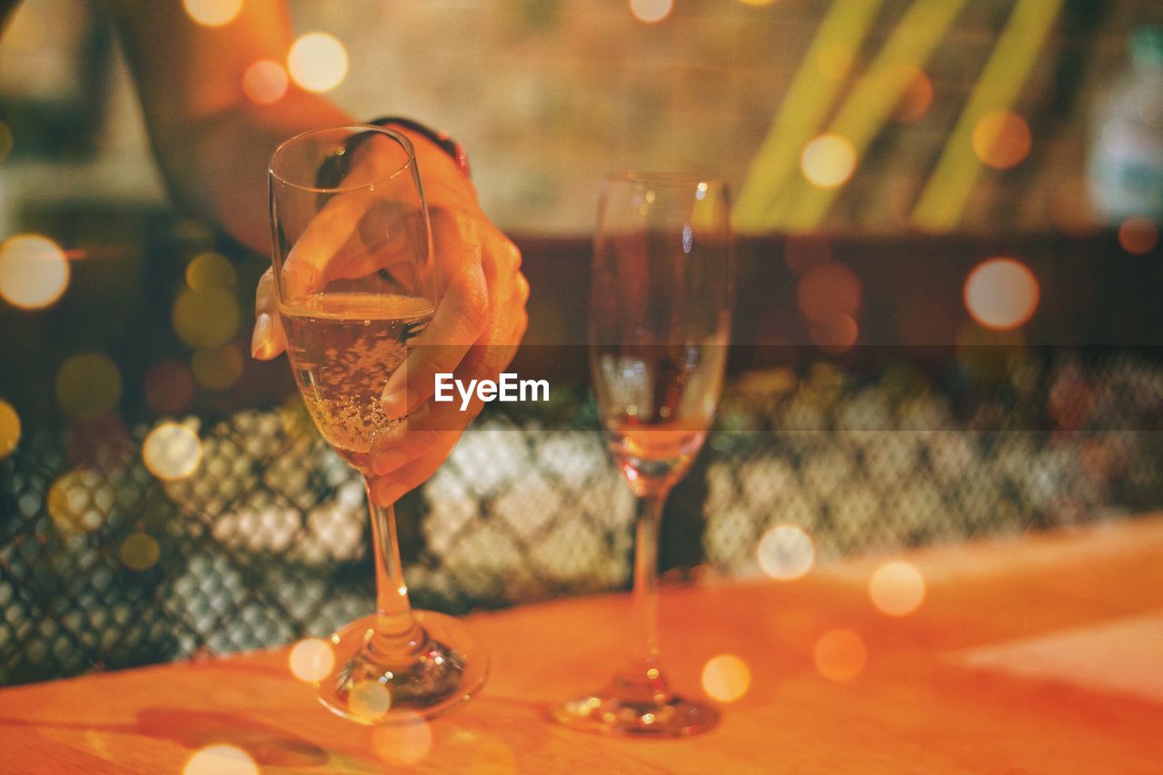 Cropped hand of woman holding champagne flute on table