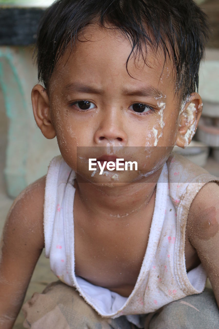 Close-up of cute boy with messy face looking away