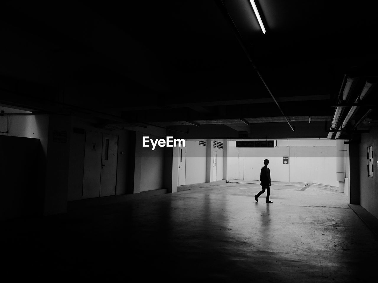 Silhouette man walking in parking garage