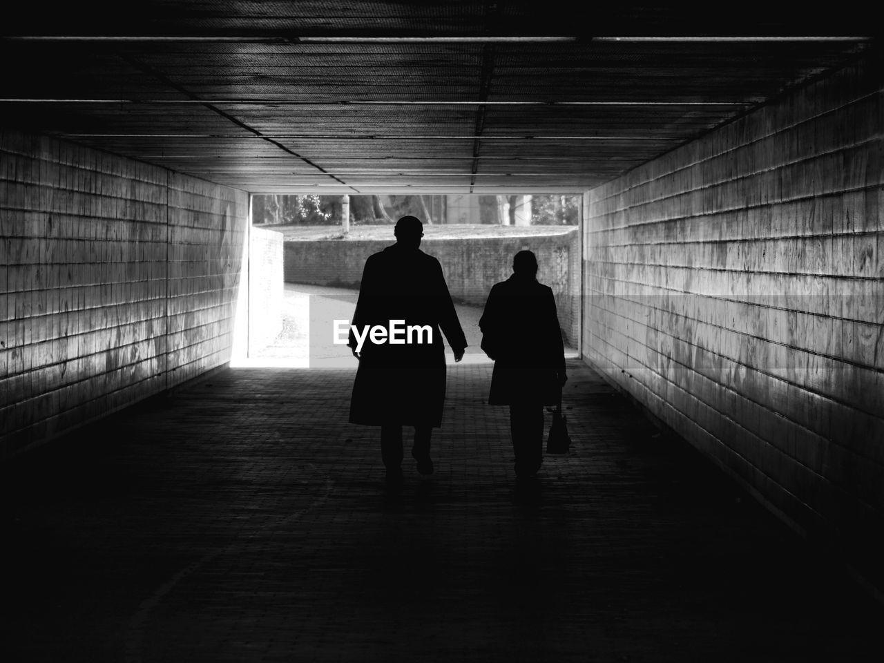 Full length rear view of silhouette people walking in tunnel