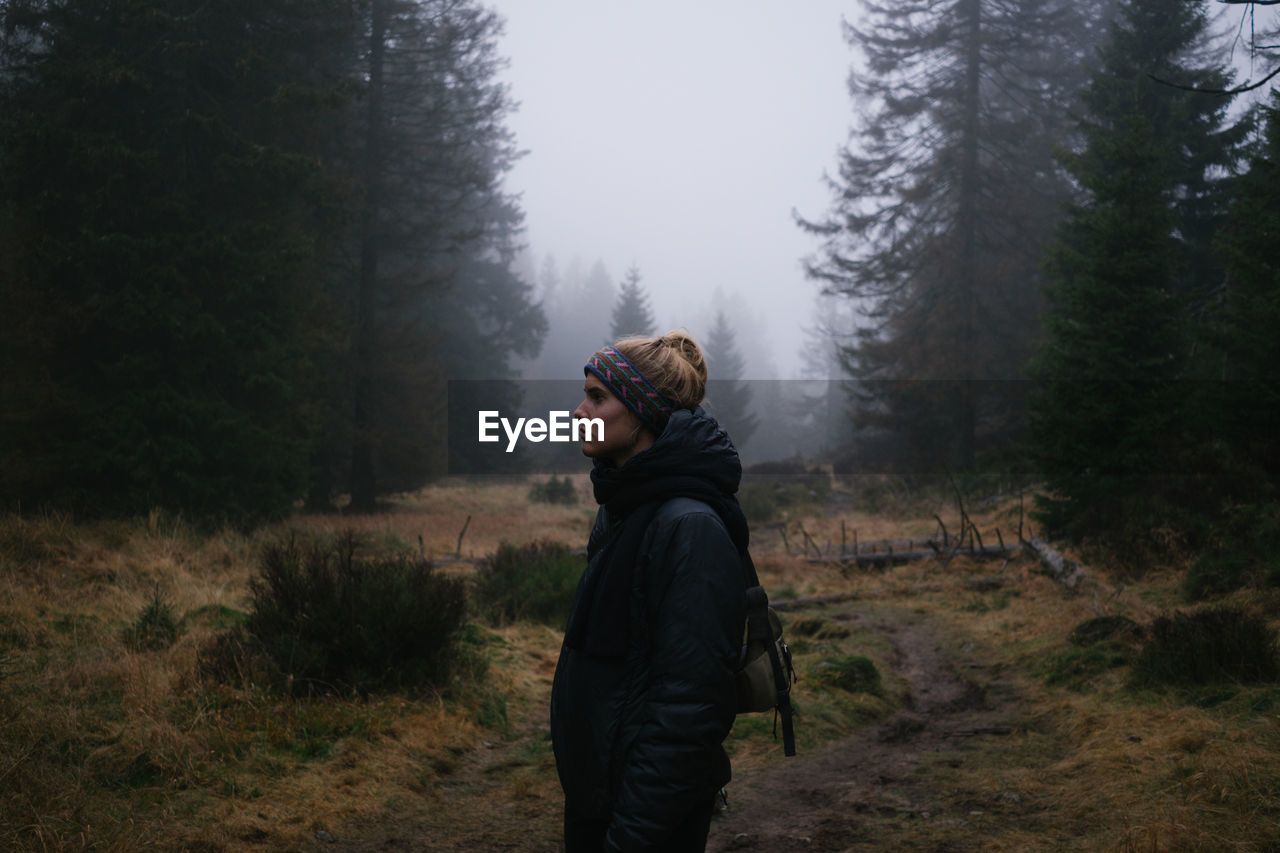 Side view of woman standing in forest