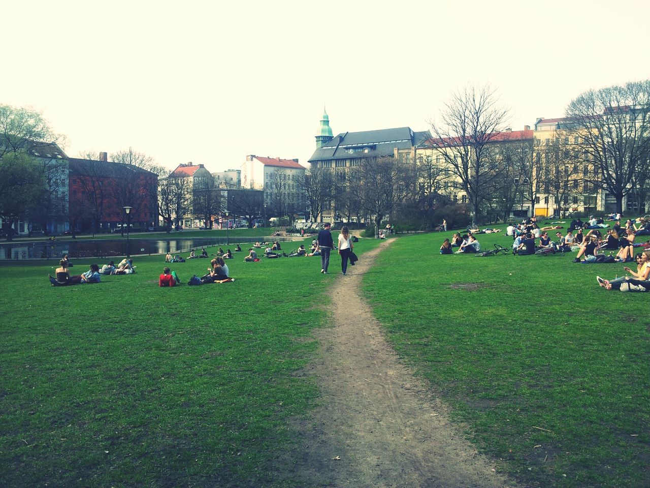 Group of people relaxing on grass against buildings
