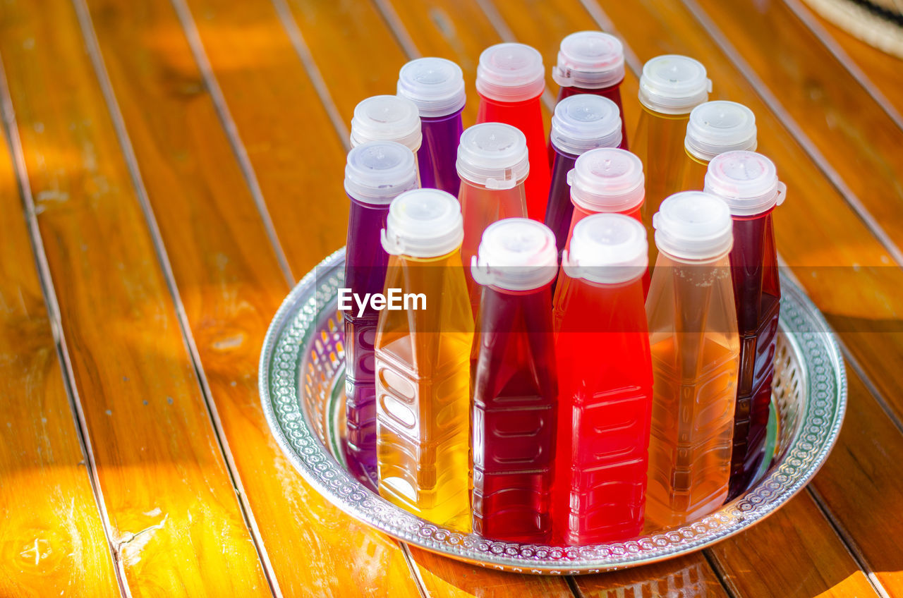 HIGH ANGLE VIEW OF BOTTLES IN GLASS ON TABLE