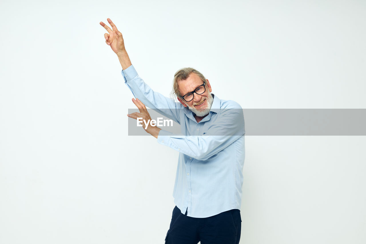 Smiling senior man dancing against white background