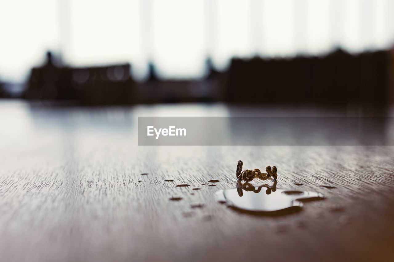 Surface level view of water drop by ring on wooden table