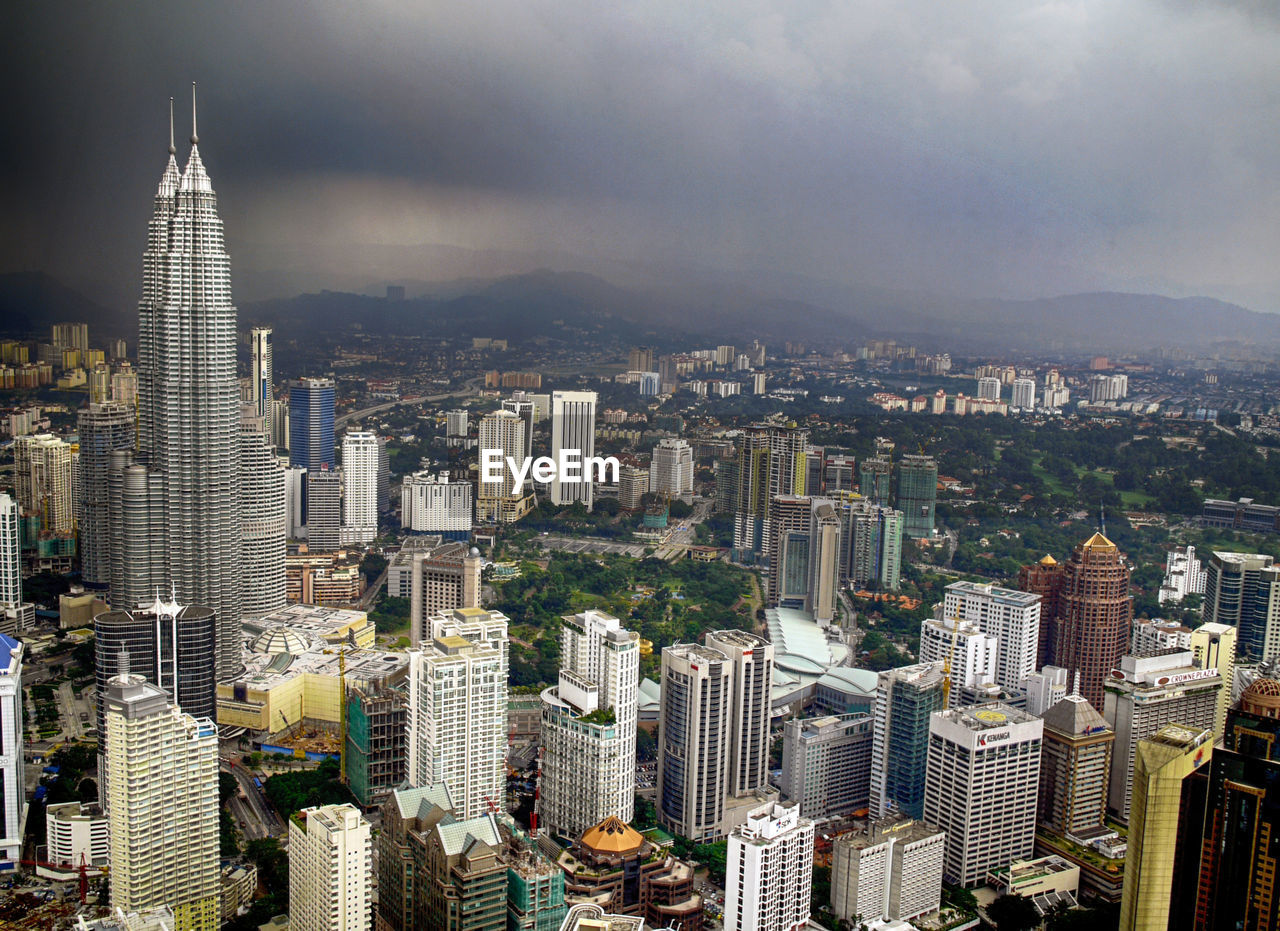 Aerial view of city buildings against cloudy sky