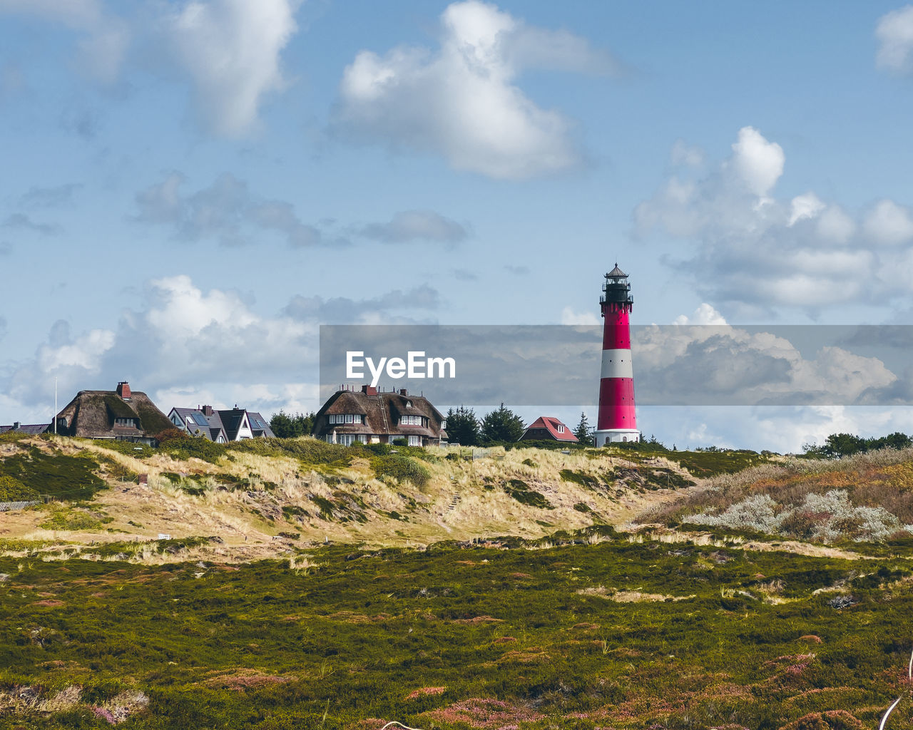 lighthouse by mountain against sky