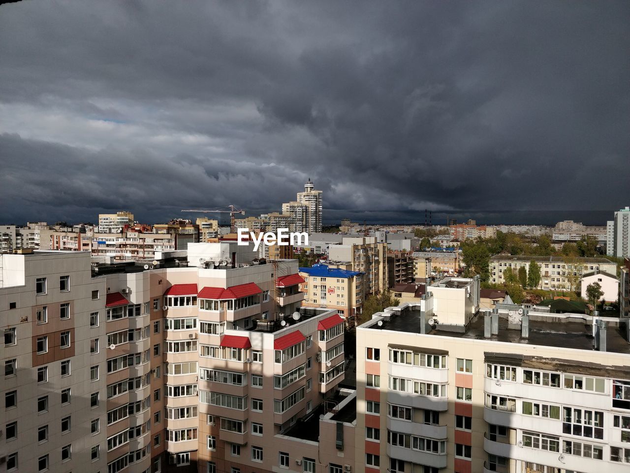 Buildings in city against dramatic sky