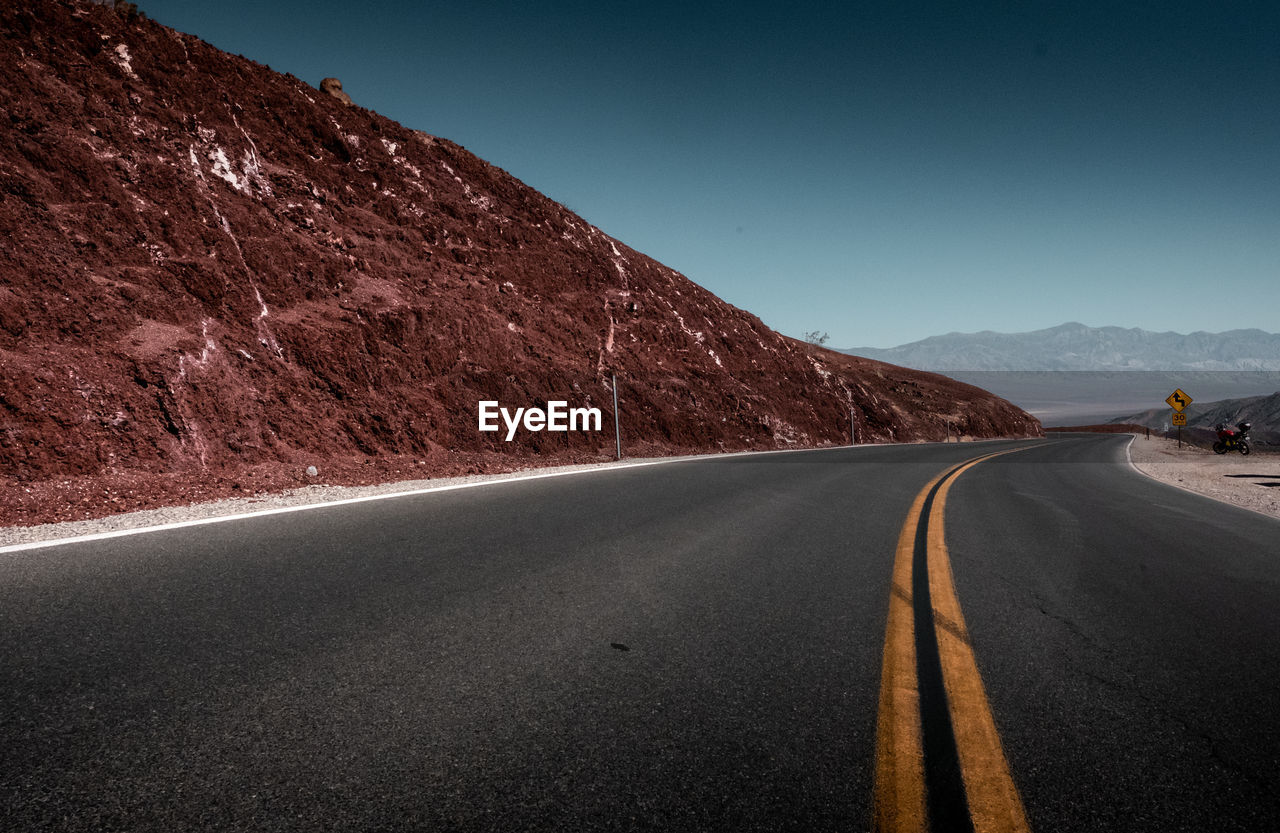 Empty road along landscape against clear sky