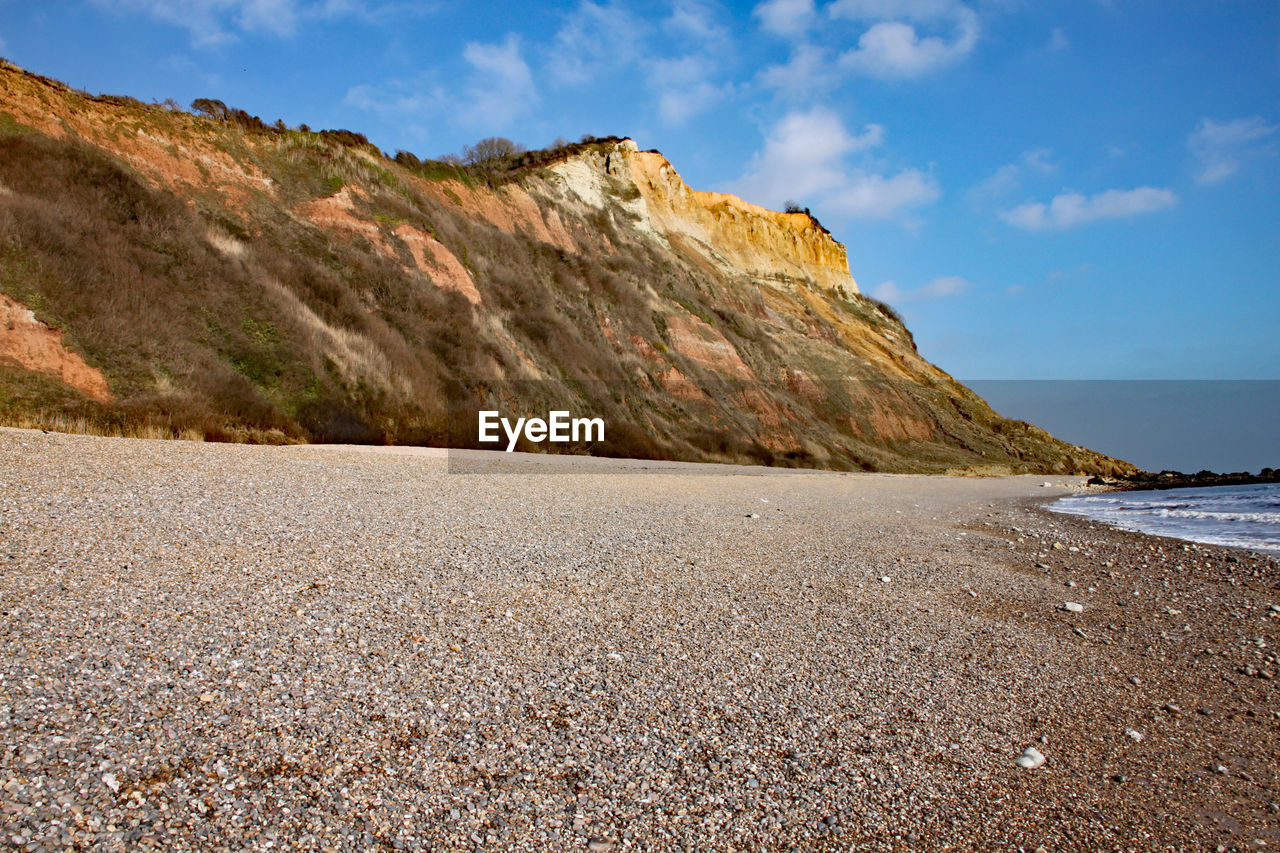 ROCK FORMATIONS ON BEACH AGAINST SKY