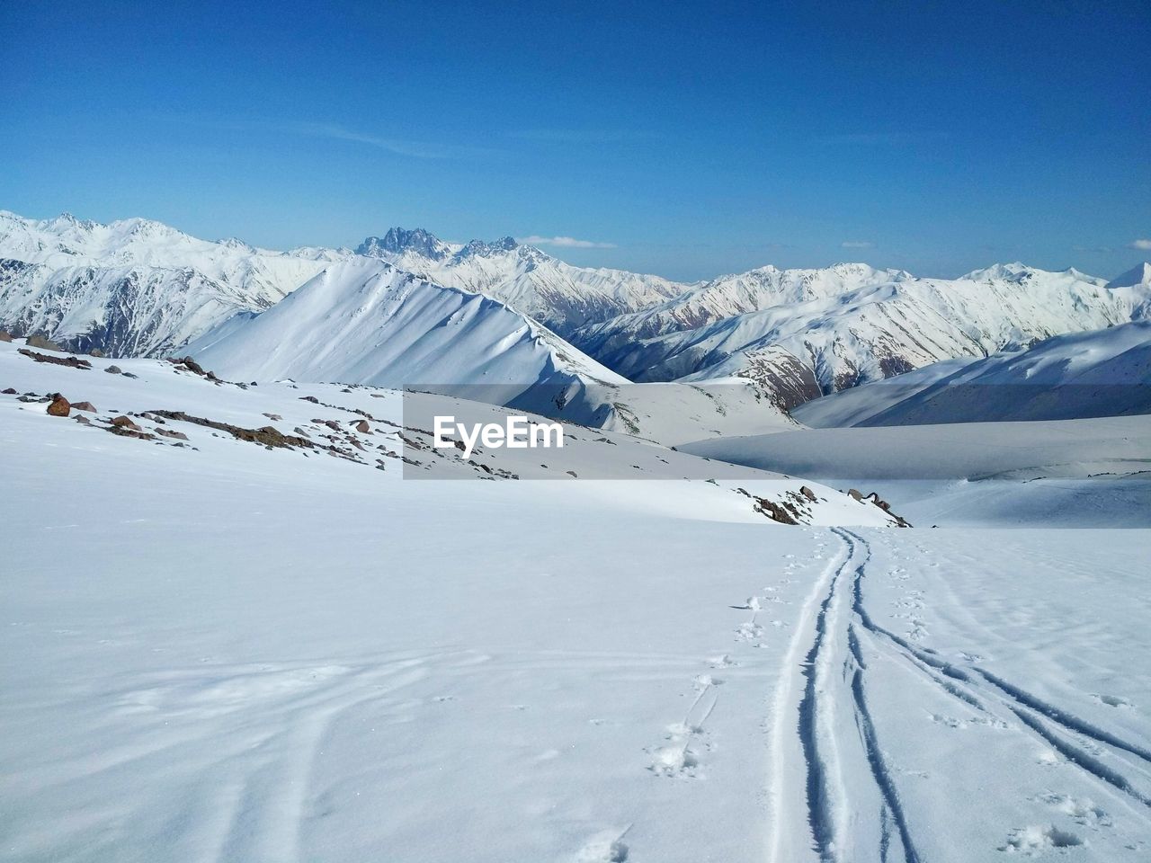 Scenic view of snow covered mountains against blue sky