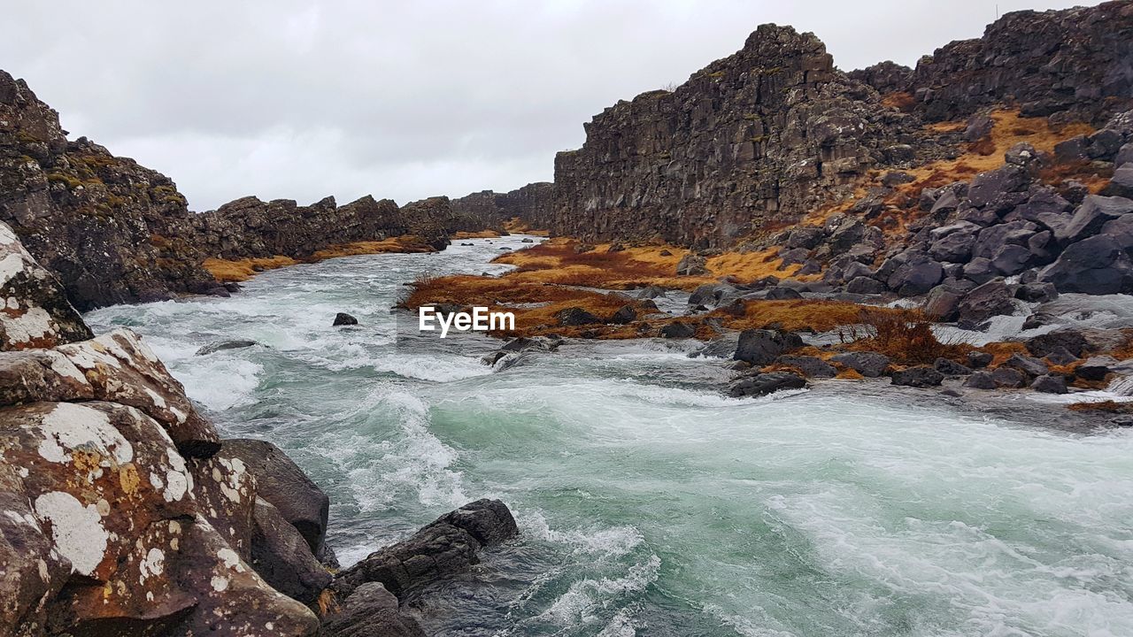 Rock formations in river gainst sky