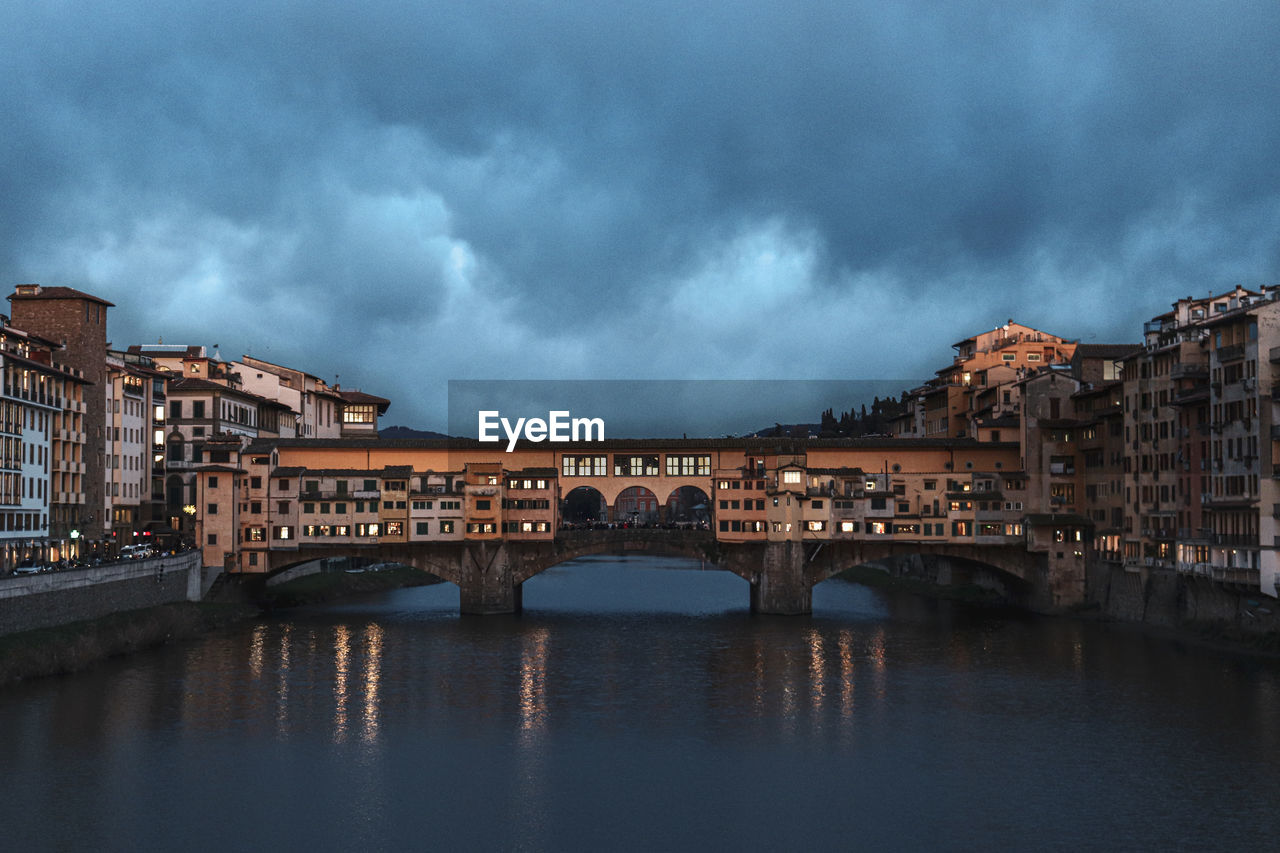 Arch bridge over river against sky in city