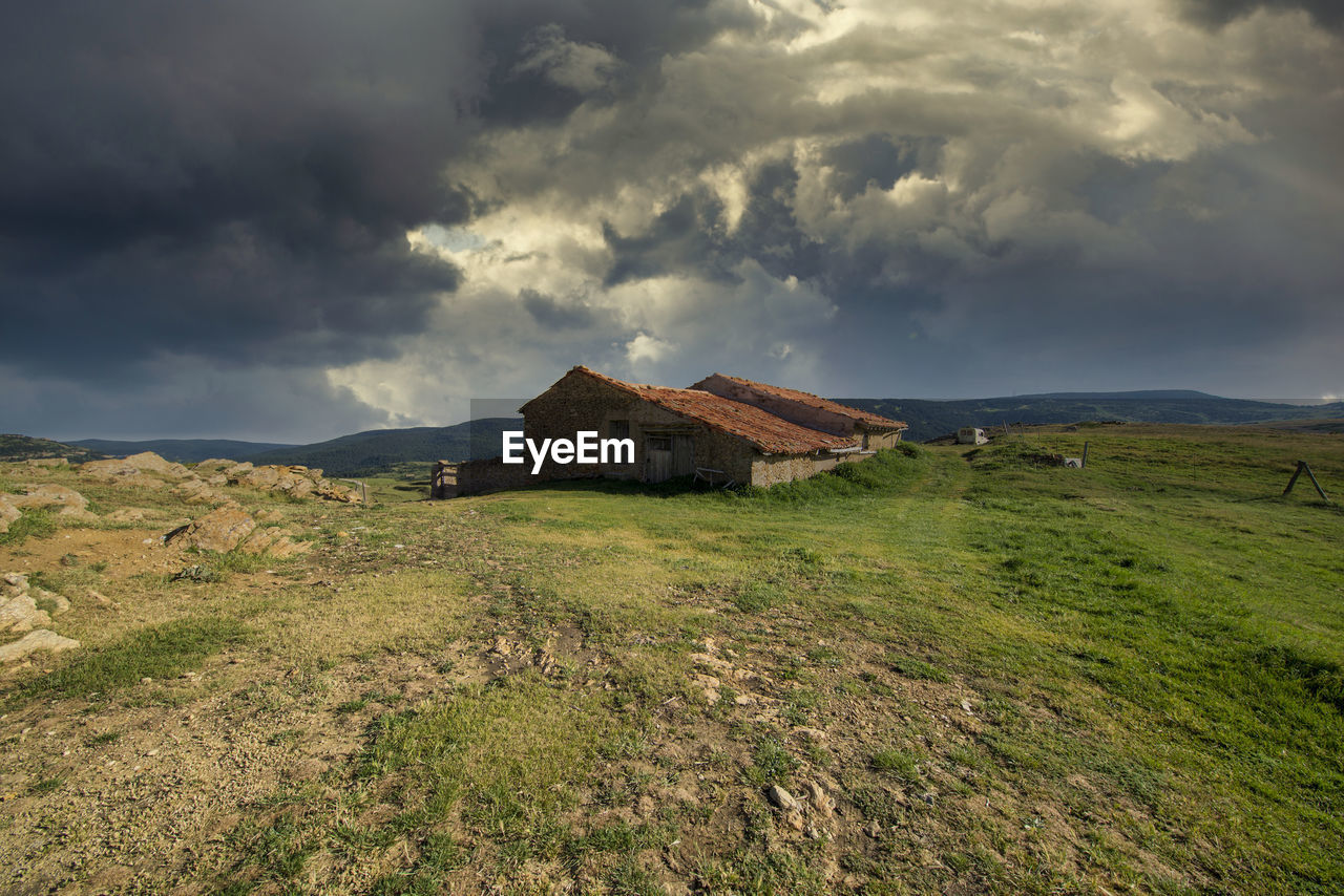 HOUSES ON FIELD AGAINST SKY