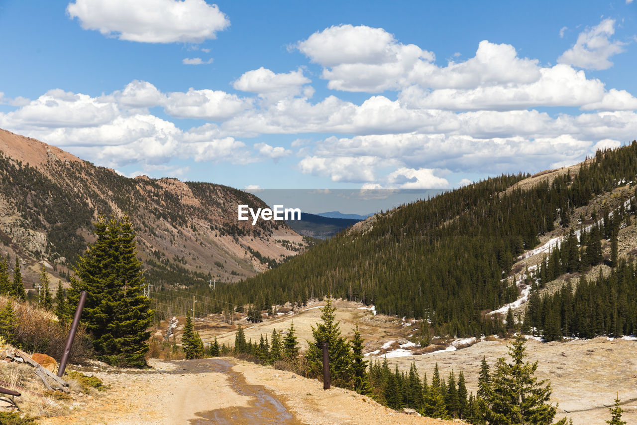 Fluffy white clouds drift over a rocky mountain landscape in colorado.