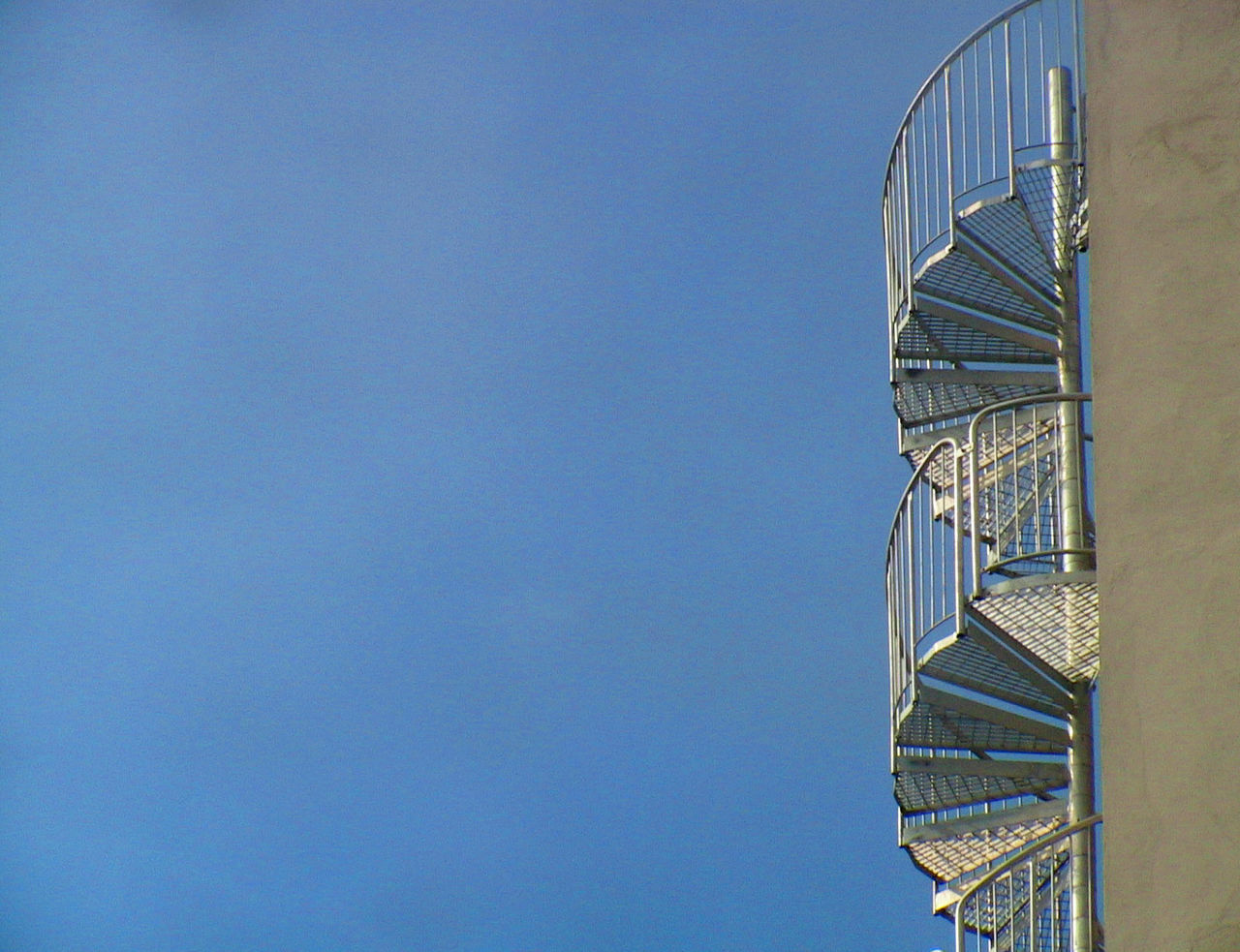 Low angle view of spiral staircase against clear blue sky