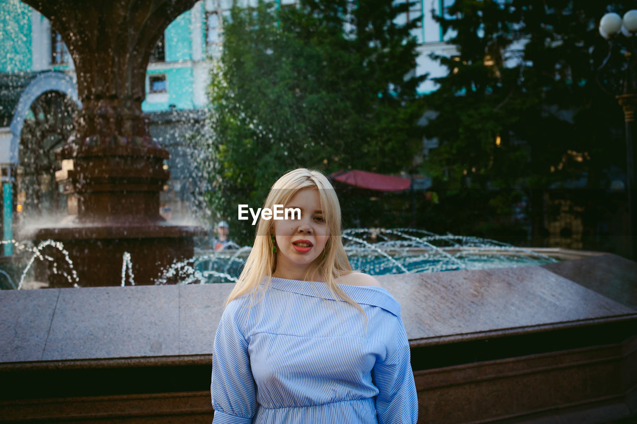 Portrait of woman standing against fountain