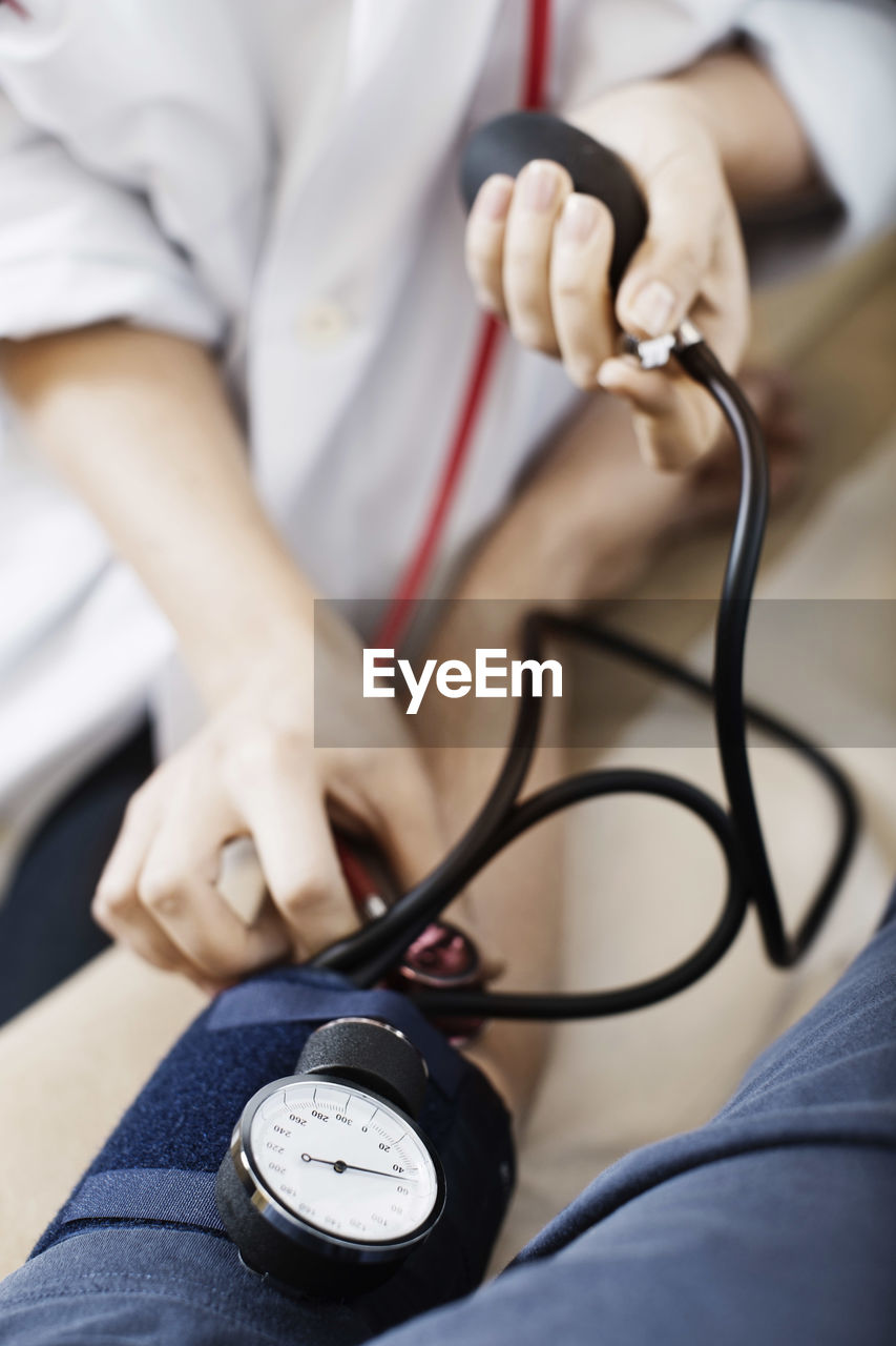 Cropped image of female doctor taking patient's blood pressure at clinic