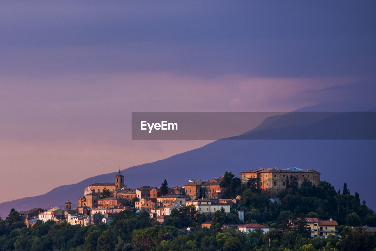 Buildings in town against sky at sunset