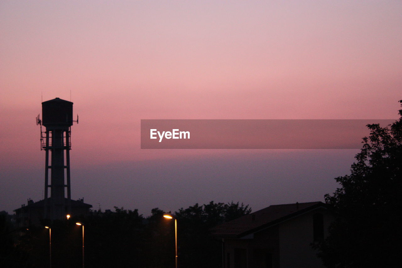 Silhouette water tower against sky at dusk