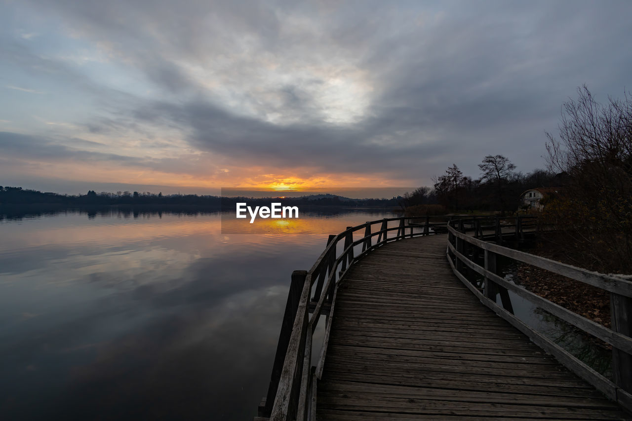 sky, water, cloud, reflection, sunset, nature, beauty in nature, scenics - nature, tranquility, evening, tranquil scene, sea, dawn, sunlight, pier, architecture, horizon, wood, no people, tree, railing, environment, landscape, outdoors, jetty, bridge, land, built structure, non-urban scene, beach, idyllic, plant, dramatic sky, the way forward, travel destinations, boardwalk, footpath, coast, sun, twilight