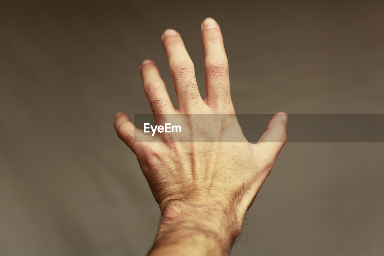 Close-up of human hand against brown background