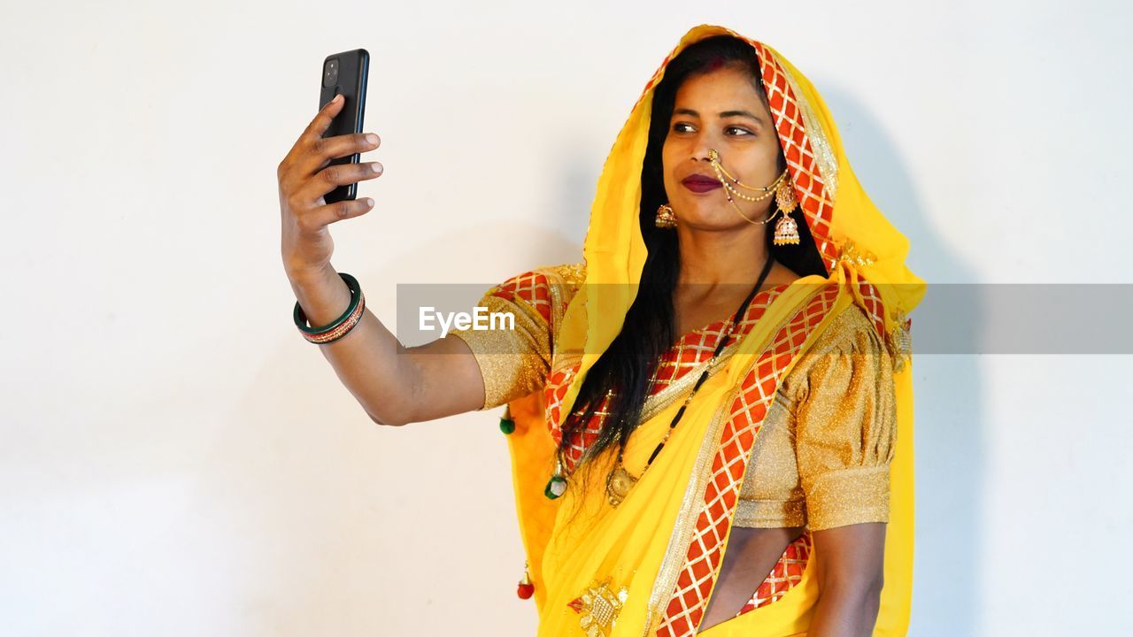 Indian ethnicity woman taking selfie on karwa chauth hindu on white background. during karwa chauth.