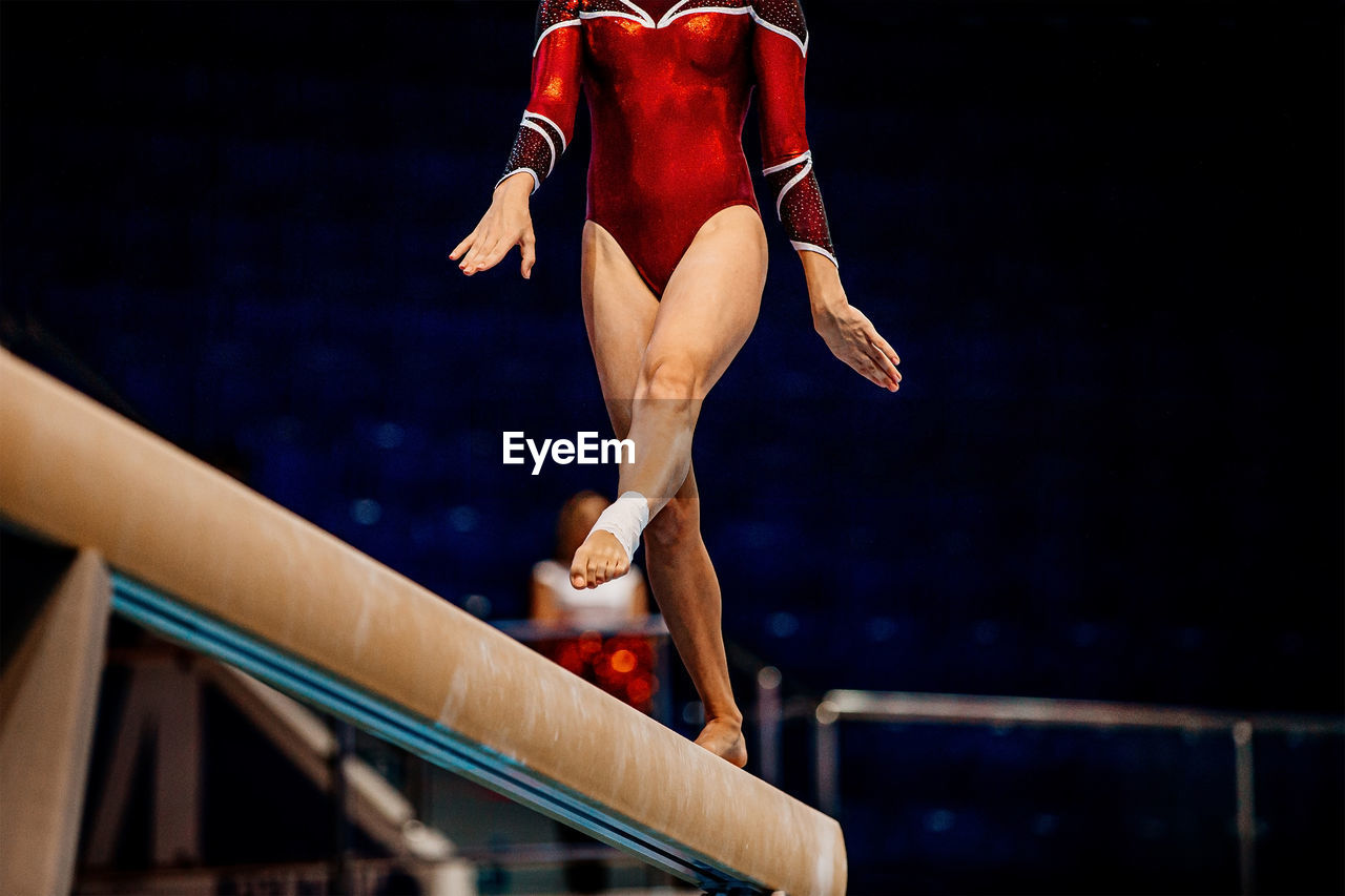 Low section of gymnast standing on wooden plank