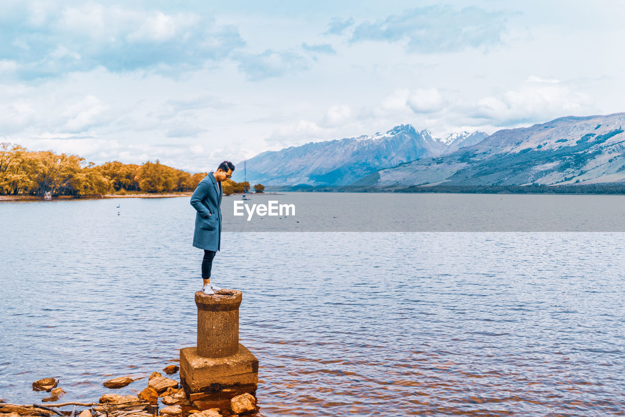 MAN STANDING IN LAKE AGAINST SKY