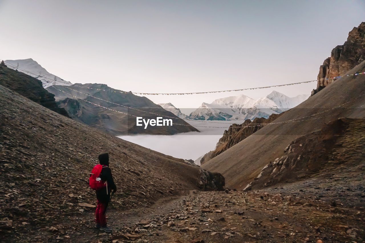 Rear view of man standing on mountain against sky