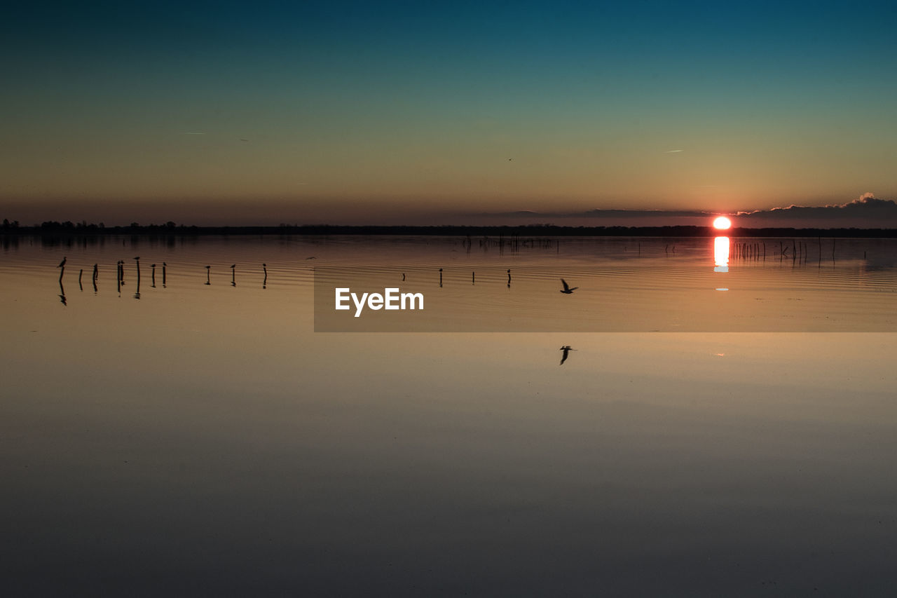 Scenic view of calm lake at sunset