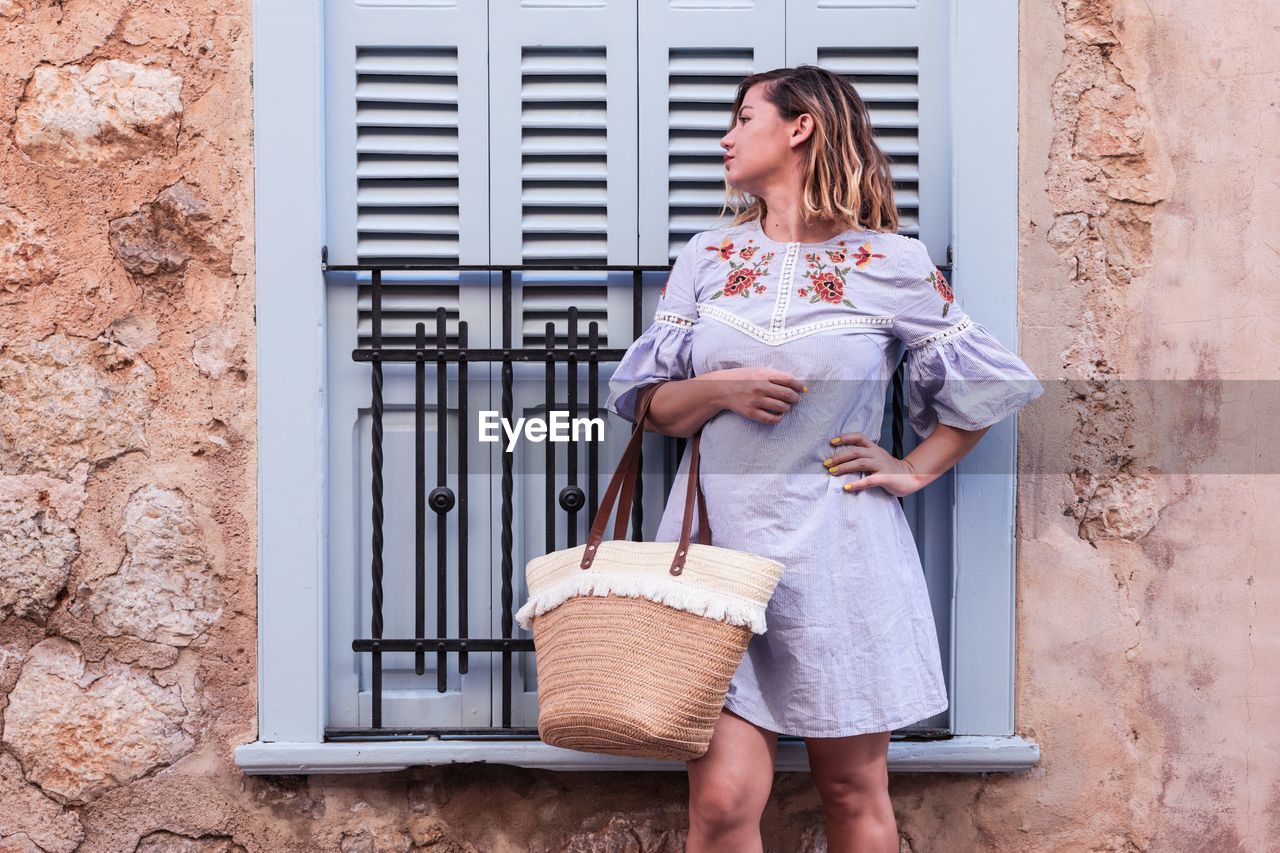 Full length of woman standing against wall