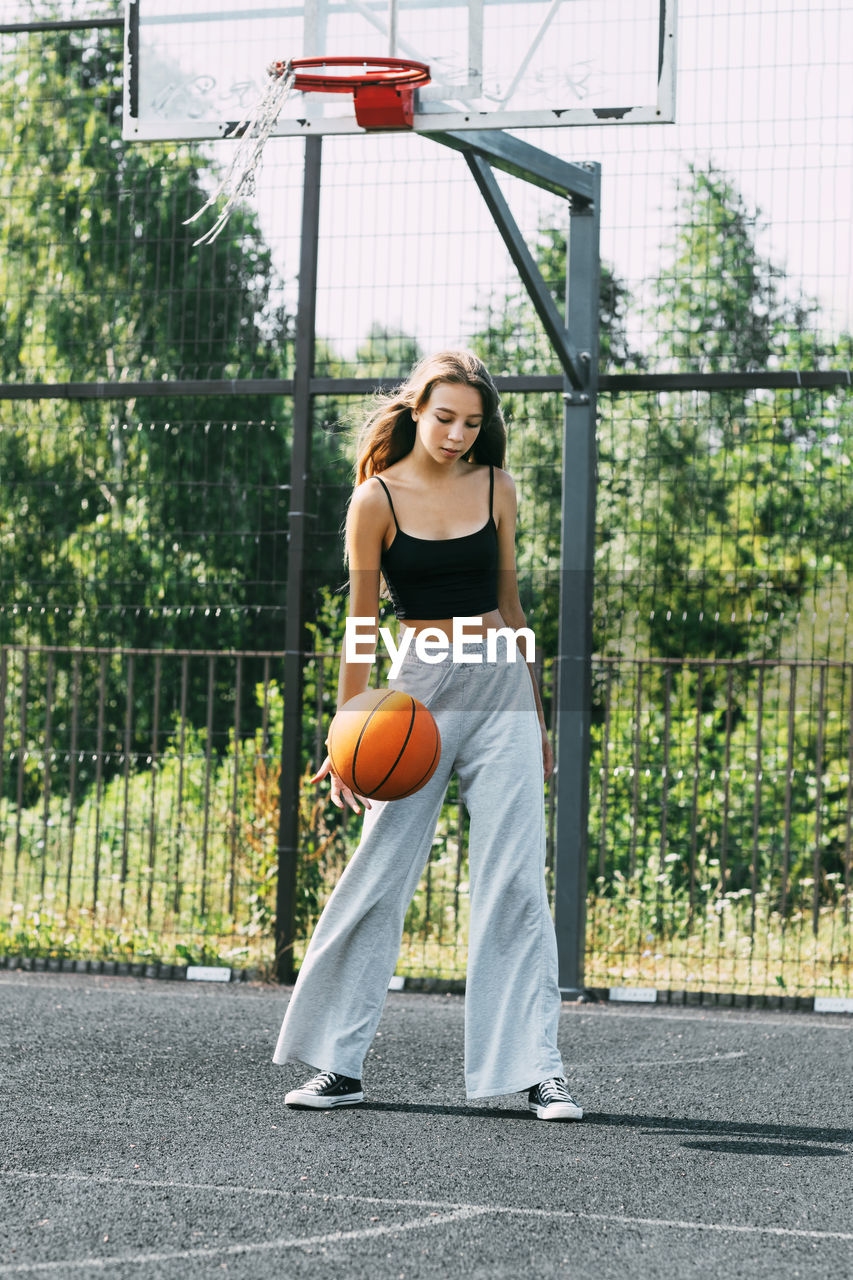 A beautiful teenage girl leads a basketball on a sports field, a girl learns to play basketball