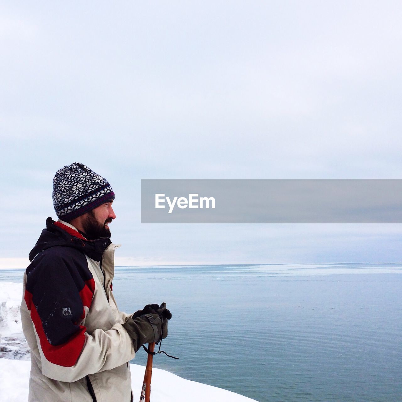 Profile shot of mid adult man in warm clothing looking at sea