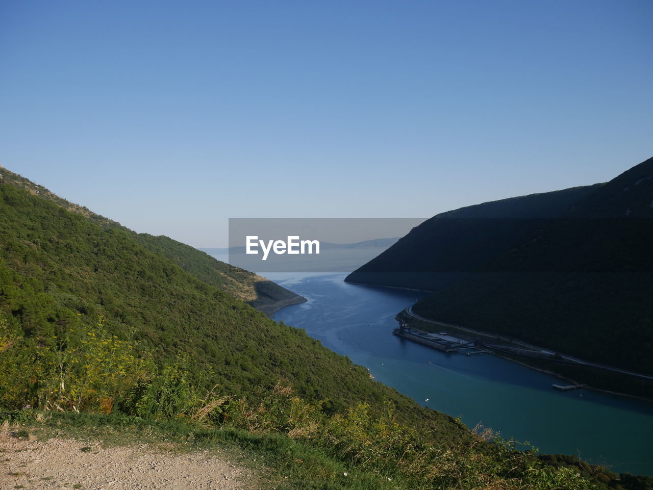 Scenic view of sea and mountains against clear sky