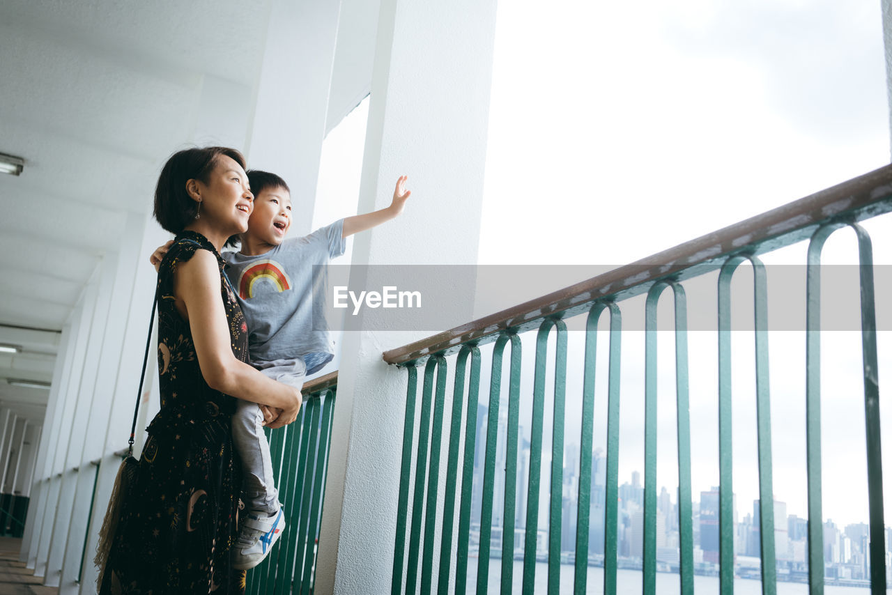 Mother carrying son while standing in corridor