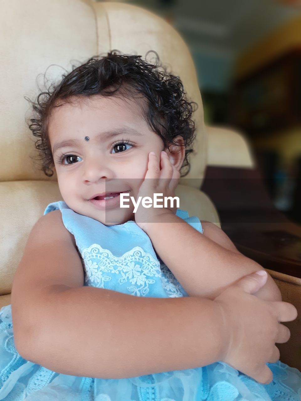 Cute smiling girl looking away while sitting on chair at home