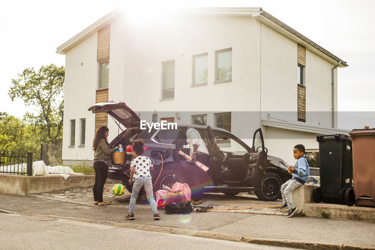 Family with electric car on driveway against house