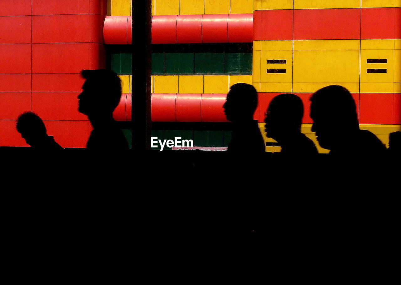 Silhouette men by window against red and yellow building