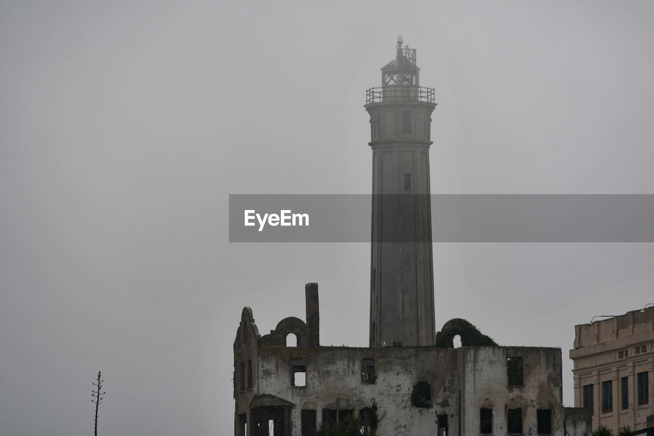 LOW ANGLE VIEW OF LIGHTHOUSE AGAINST BUILDINGS