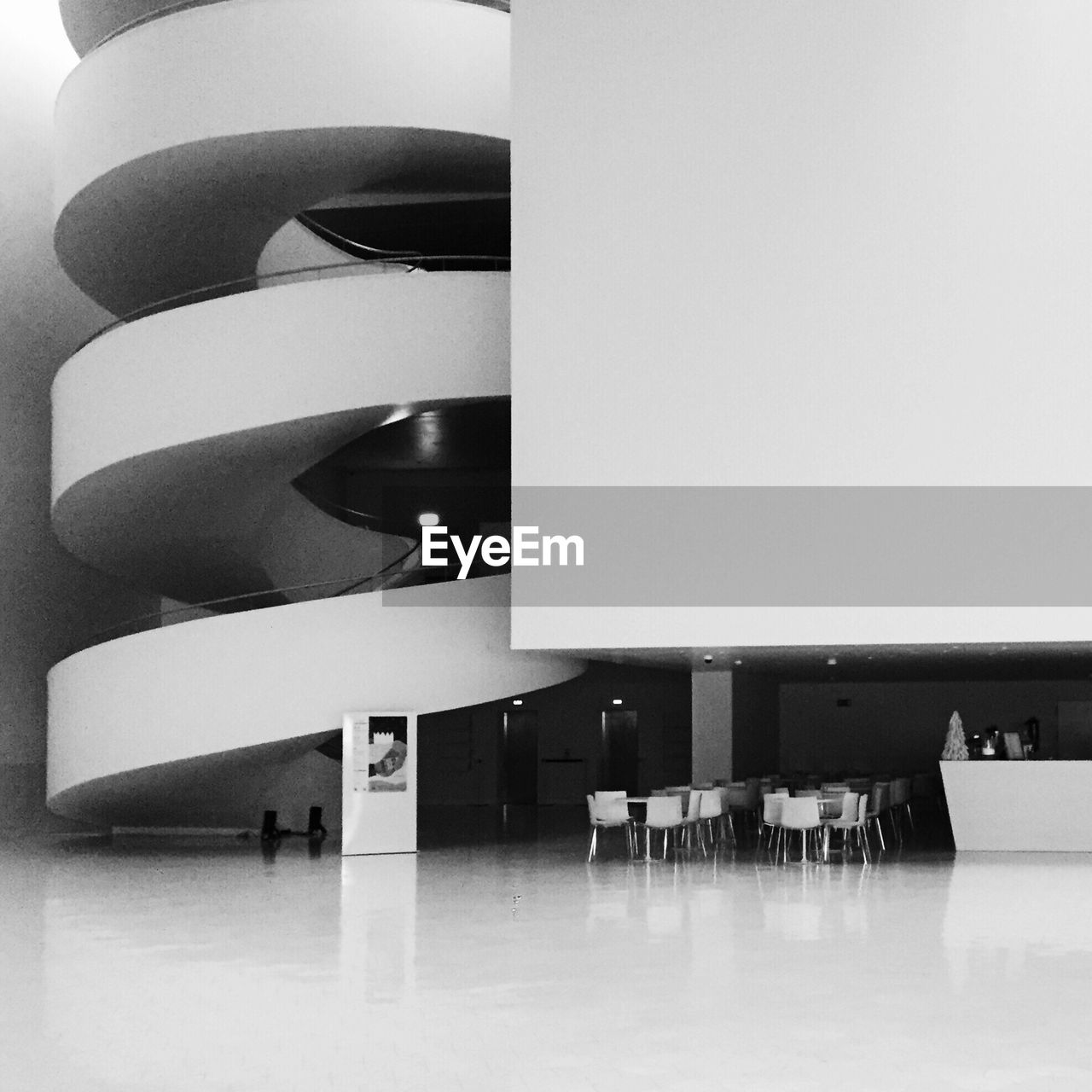 Empty chairs on flooring by spiral stairs