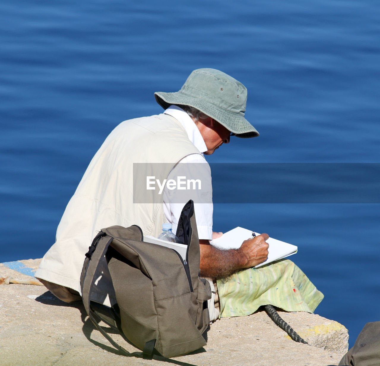 Man writing in book while sitting at beach