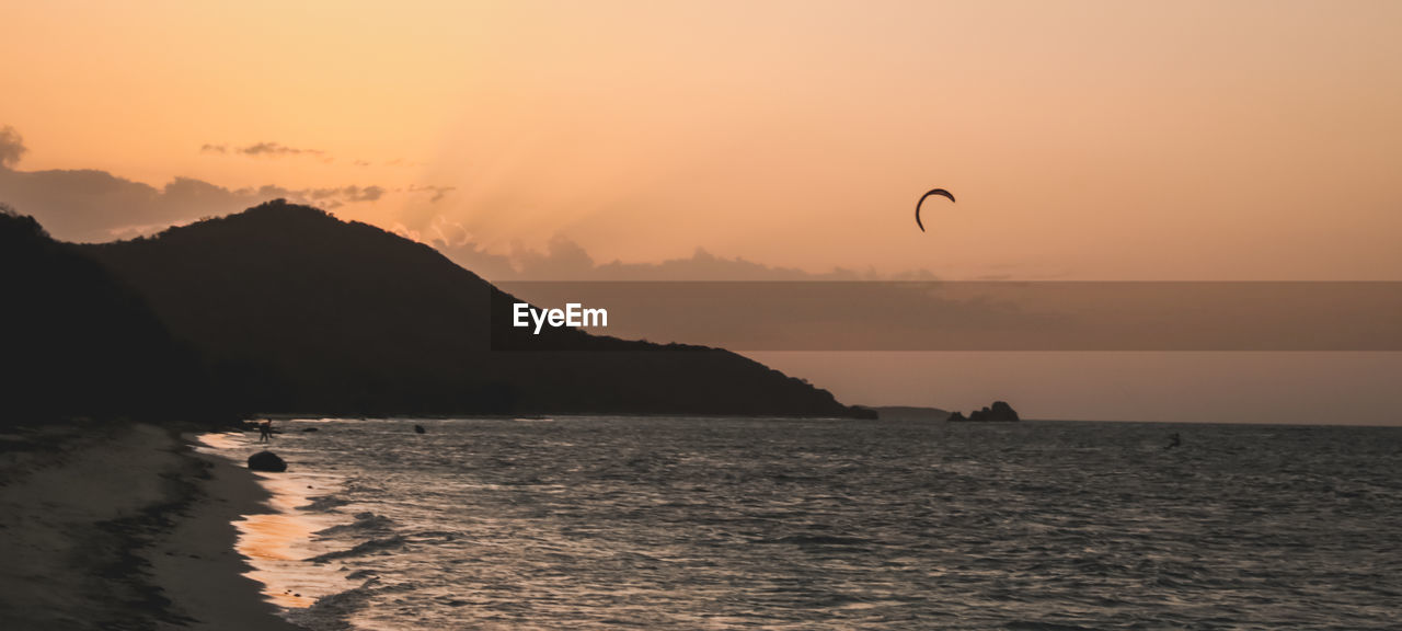 Scenic view of sea against sky during sunset and some kite surfing 