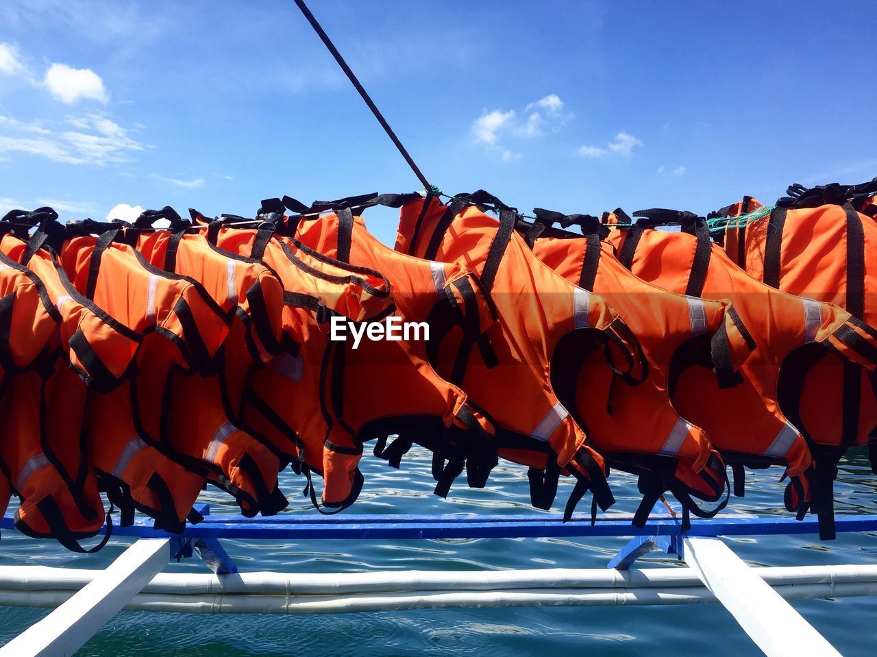 Life jackets drying on clothesline against sky