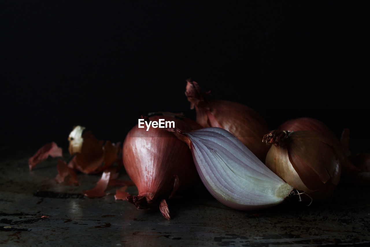 Close-up of onions on table against black background