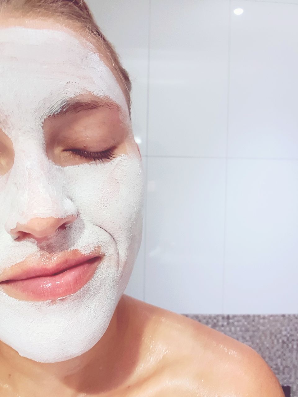 Close-up of woman with eyes closed and facial mask in bathroom